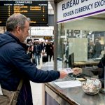 Traveller exchanging pounds at train station counter