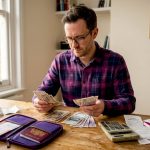 Man reviewing foreign currency at a home desk