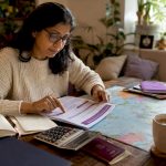 Traveller planning currency exchange at home table