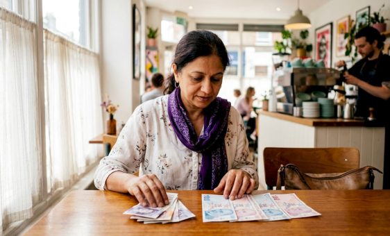 Woman examining British pounds and Turkish Lira banknotes