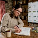 Woman planning UK travel budget at home table